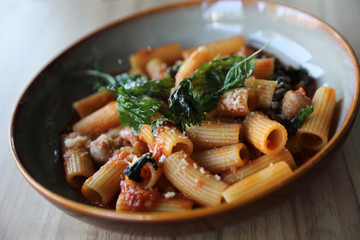Pasta with sausage in tomato sauce on wood background , italian food