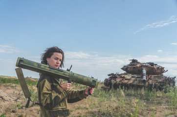 girl in uniform with a Bazooka on the background of a broken tank
