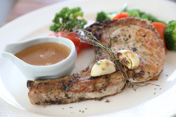 grilled pork chop with vegetable on dish with wood table background