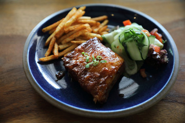 barbecued pork ribs steak with fresh vegetables on an old rustic wooden in restaurant