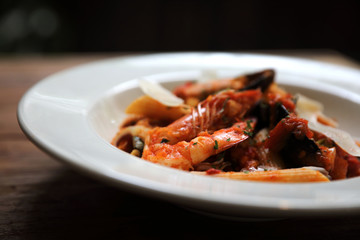 Penne pasta tomato sauce arabiata with seafood on wood background vintage style