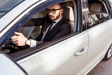 handsome driver in suit and glasses driving car
