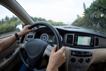 driver hands on wheel driving car on city street