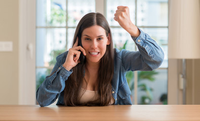 Young woman using smartphone annoyed and frustrated shouting with anger, crazy and yelling with raised hand, anger concept - obrazy, fototapety, plakaty