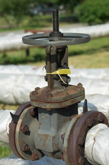 Rusty controlling faucet crane. Round handle of water supply valve close-up. Industrial heating and water supply systems
