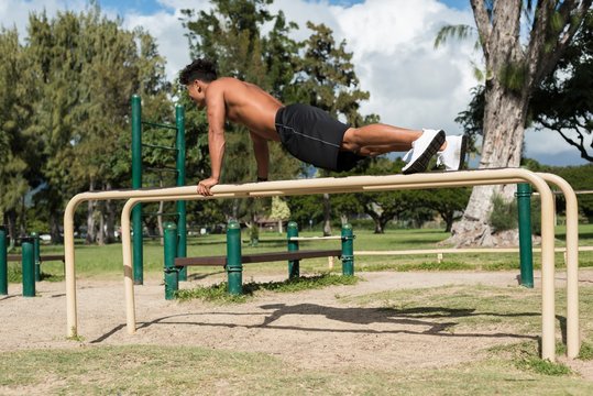 Man exercising on parallel bar in the park