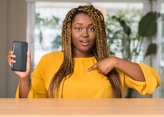 African american woman using smartphone with surprise face pointing finger to himself