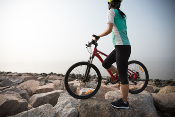 woman cyclist with mountain bike on seaside