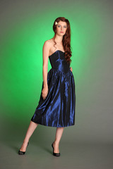 Fototapeta premium Girl in dark blue dress in studio on green background