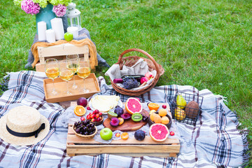 Picnic background with white wine and summer fruits on green grass, summertime party
