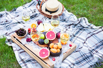 Picnic background with white wine and summer fruits on green grass, top view