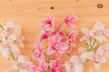 bunch of artificial blooming orchid flowers on wooden background. Interior decoration.