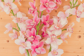 bunch of artificial blooming orchid flowers on wooden background. Interior decoration.
