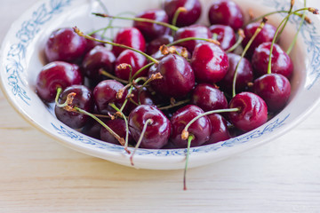 top view of cherry in rustic white plate on wooden table.