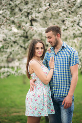 Obraz premium Young couple in love resting in the blooming garden. white blooming trees
