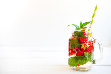 Homemade iced lemonade with mint, summer fruits and berries in a mason jar. Copy space background