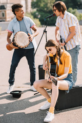 Young and happy multiracial male and female street musicians in city