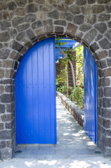 Old blue wooden garden door on stone wall