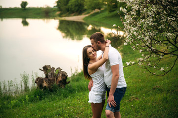 Fototapeta premium Dating in park. Love couple standing together on grass near the lake. Romance and love