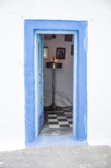 Old blue wooden open church door on white wall, santorini