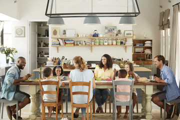 Two families having lunch together in the kitchen at home