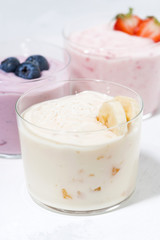 Fototapeta na wymiar sweet yoghurts with fruits and berries on white background, vertical closeup