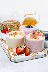 sweet yogurts with fruit and berries for a delicious breakfast on white table, vertical