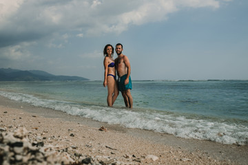 .Lovely couple on vacation in the gili islands enjoying at the lonely beach with turquoise blue water, relaxing and sunbathing. Travel photography.