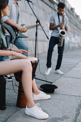 Talented street musicians with guitar, drum and saxophone performing in city