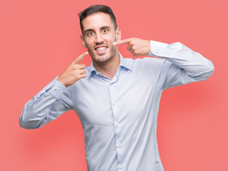 Fototapeta premium Handsome young businessman smiling confident showing and pointing with fingers teeth and mouth. Health concept.