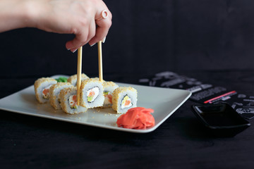 Rolls on a white plate on a black background with ginger and vassabi