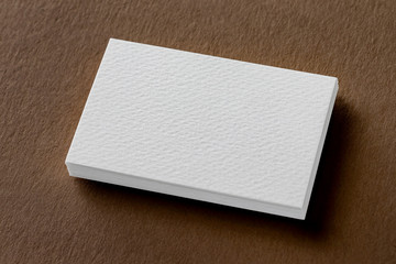 Mockup of white business cards stack at brown craft paper background.