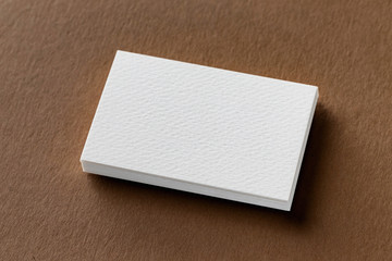 Mockup of white business cards stack at textured brown craft paper background.