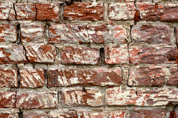 Rugged cracked vintage red brick wall with white patina close-up