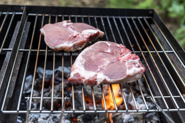 Raw T-bone chop of pork on the grill