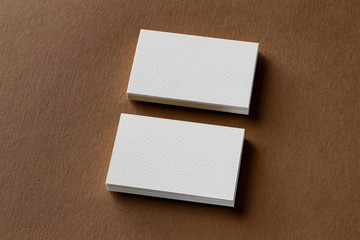 Top view mockup of two white business cards stacks at brown craft paper background.