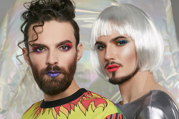 Closeup portrait of a  transgender couple. 2 male persons with make up on their faces, one rocking...