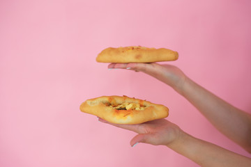 pie with cheese in the hands on a pink background