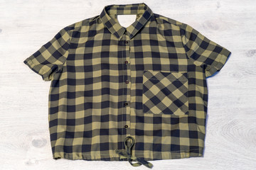 Checkered women's shirt lying on a light wooden background