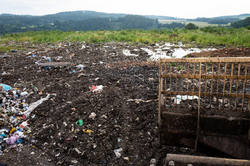 Garbage pile in trash dump or landfill with green nature in the background