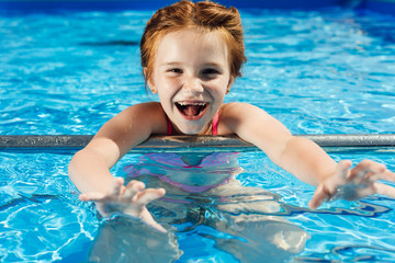 Fototapeta na wymiar close-up portrait of adorable little child in bikini in swimming pool looking at camera