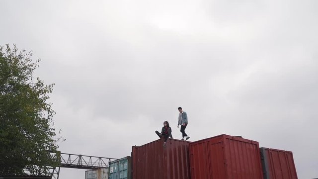 Couple walk on a freight container.