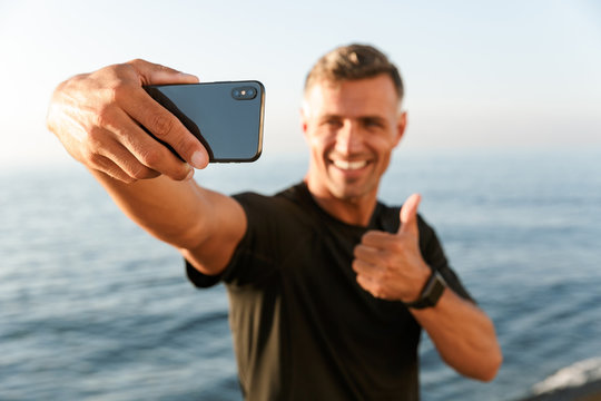 Smiling handsome shirtless sportsman taking a selfie