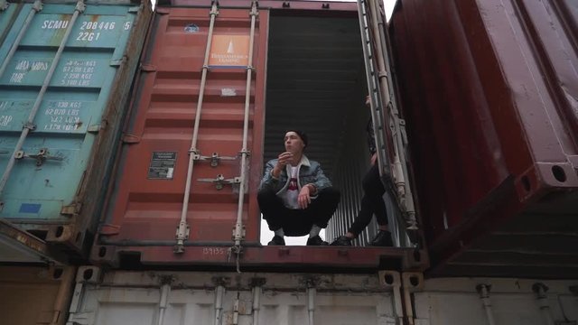 Young man smokes sitting in the freight container.