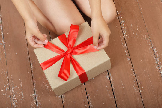 Gifts, shopping and present - Gift box is tied in the girl's hands wooden background