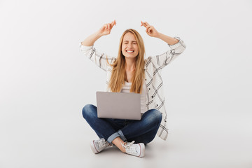 Portrait of excited young casual girl using laptop computer