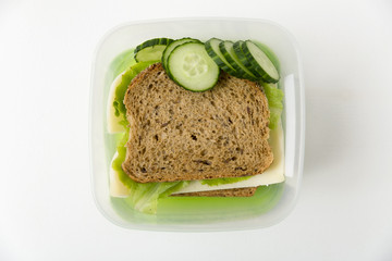 Lunch box with cheese and lettuce sandwich and fresh cucumber. Lunch, break, healthy snack