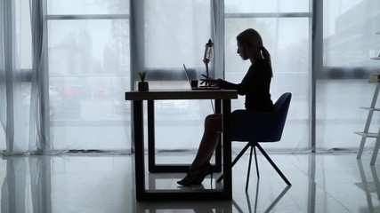 secretary works on laptop in office.
