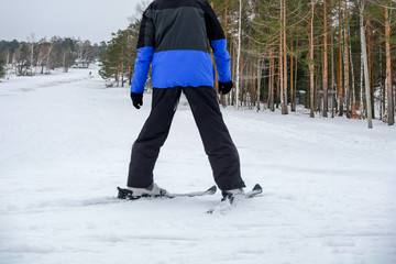 Fototapeta na wymiar Young man on ski in black and blue winter season jacket on mountain snow track