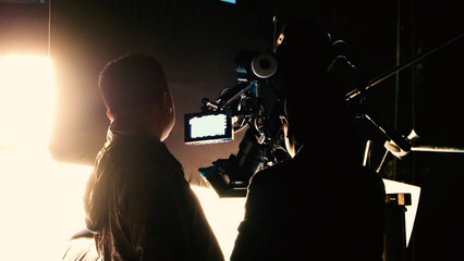 Blurry images of silhouette people film crew team working behind the scenes for shooting video...
